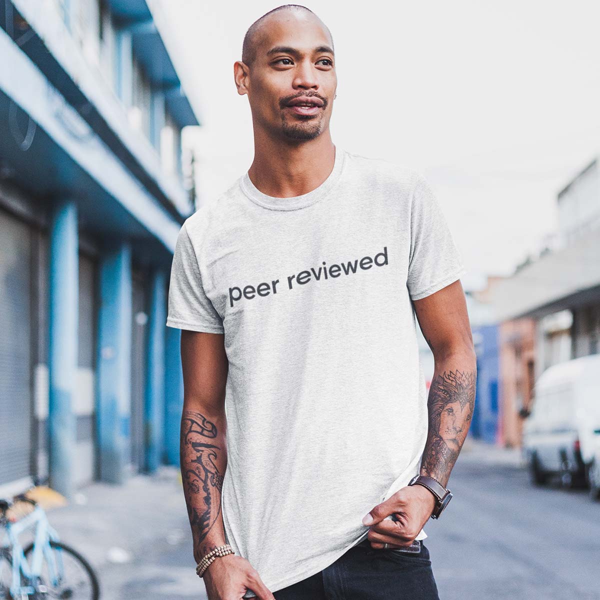 Man wearing a white t-shirt with 'peer reviewed' text on a street. Science t shirt, science tee, unisex science t shirt, short sleeve t shirt, short sleeve science t shirt